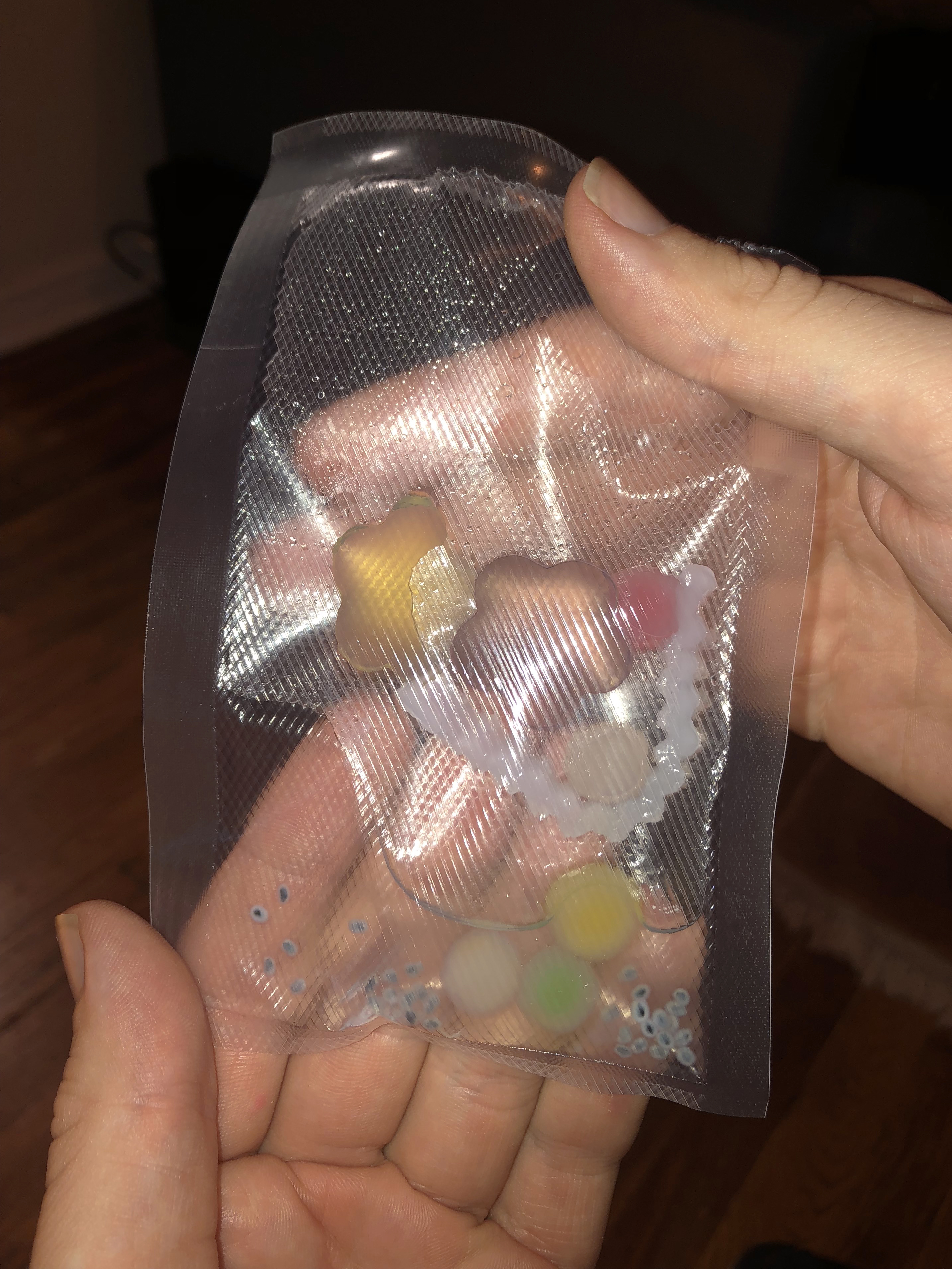 A hand holding a half empty clear pouch of jelly snacks
